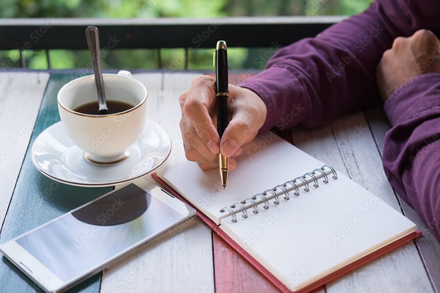 Carta de despedida del año: Reflexiones y agradecimientos 1 imagen de una pluma escribiendo en un papel con una taza de cafe al lado
