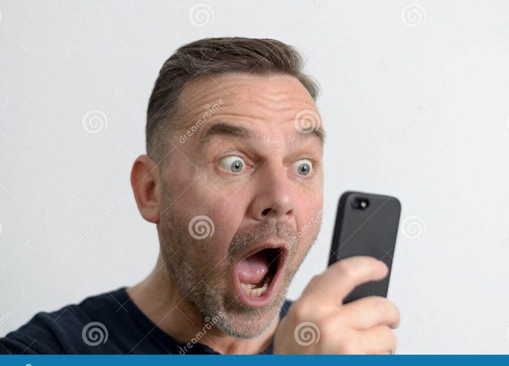 ¿Amigo virtual revela secretos? Descubre cómo actuar 1 un hombre mirando fijamente su telefono movil con expresion de sorpresa