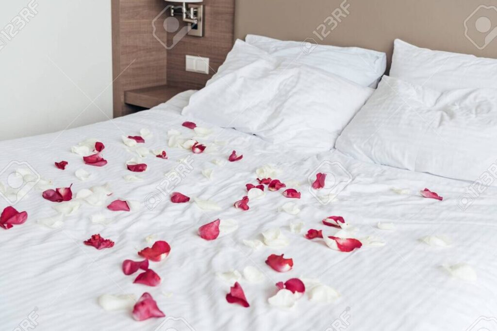 Las 10 mejores frases para velar tu sueño y demostrar amor 1 una imagen de una hermosa cama con sabanas blancas y suaves adornada con petalos de rosa roja y una vela encendida
