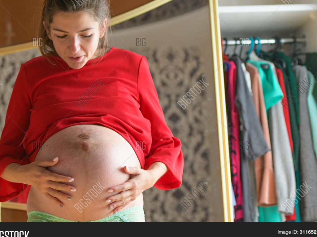 10 formas de demostrarle a mi papá cuánto lo amo desde el vientre 1 una imagen de una mujer embarazada sosteniendo su vientre sonriendo y mirando hacia abajo con amor