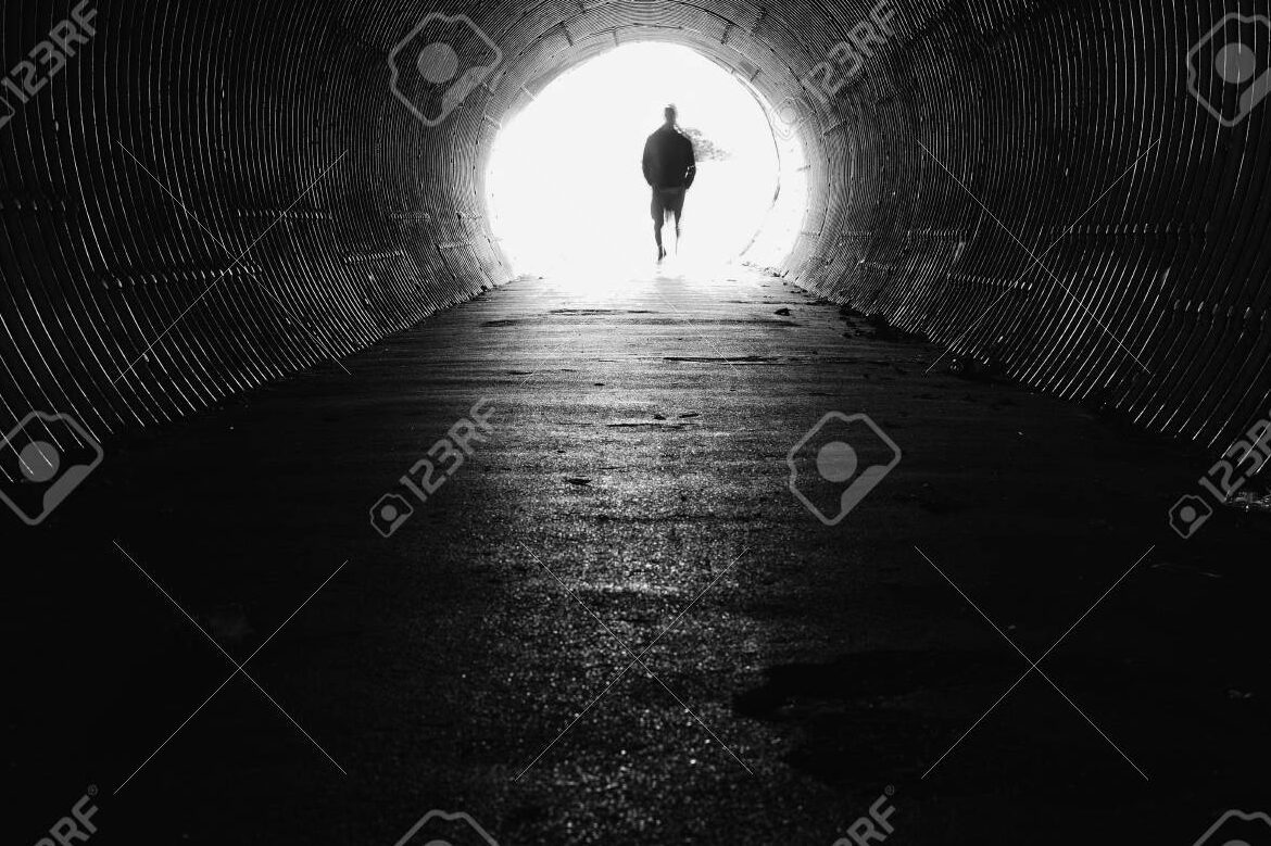 una imagen de una persona caminando hacia la luz al final de un tunel oscuro 1