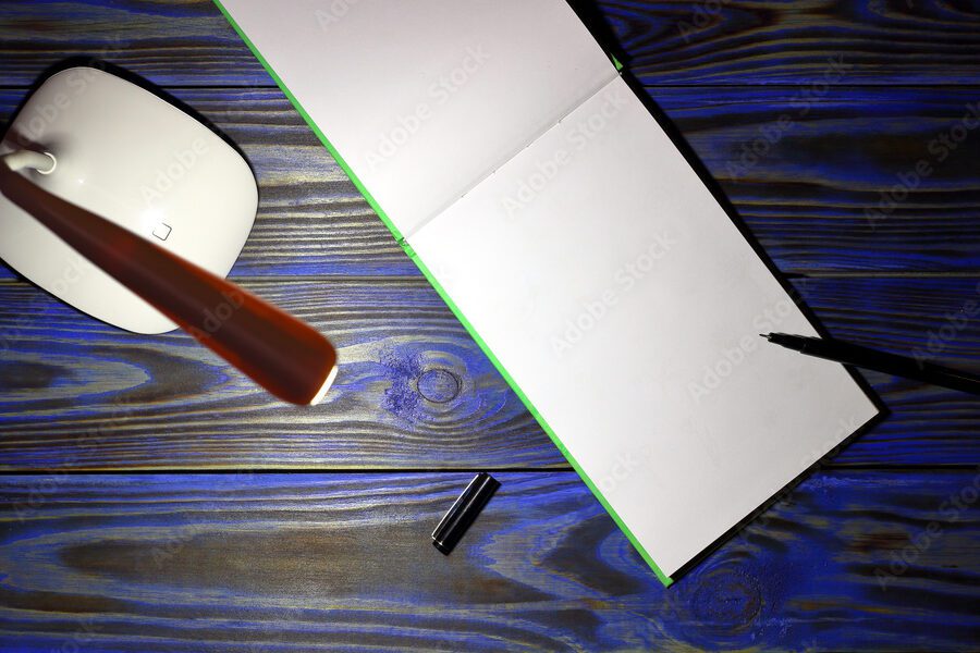 una imagen de una pluma y una hoja de papel con una lampara de escritorio encendida de fondo