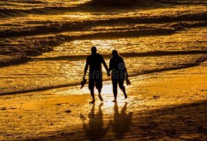 Frases de amor para expresar tus sentimientos en su pecho 2 una pareja cogidos de la mano caminando por la playa al atardecer