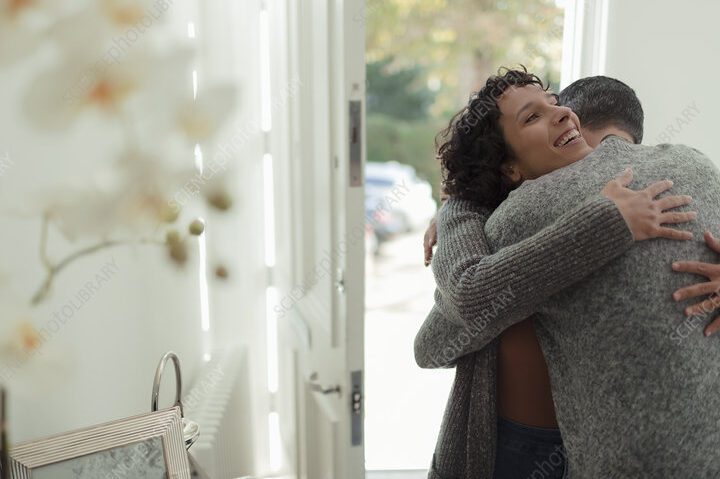 5 ideas para sorprender a tu esposo con una bienvenida inolvidable 1 una pareja feliz abrazandose y sonriendo en la puerta de su hogar