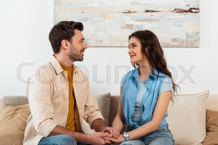 Recuperando el amor: Cómo reconstruir tras una discusión 1 una pareja sentada en un sofa mirandose fijamente y sonriendo